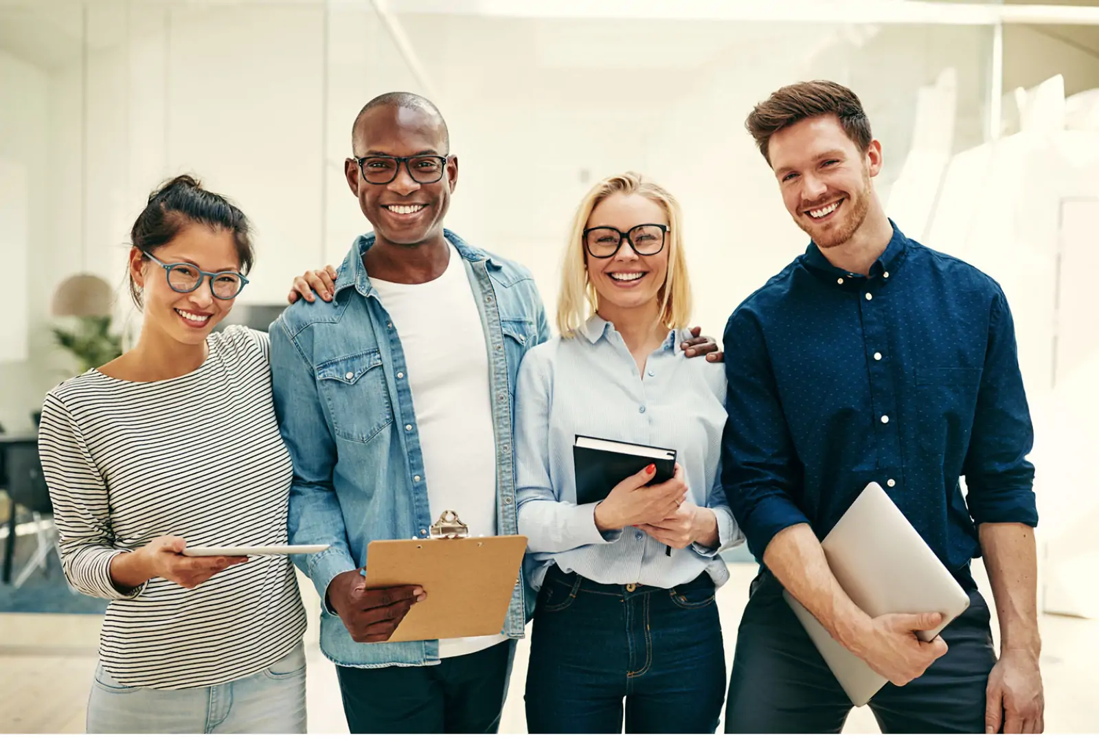 Happy diverse team holding laptops and notepads