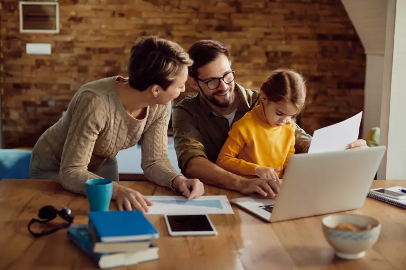 happy working father using laptop with his family home